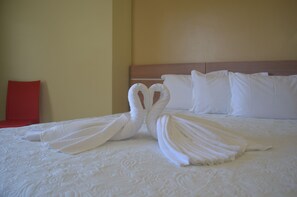 A neatly made bed with white linens and two towels arranged in a heart shape. - Pontal Praia Hotel (Porto Seguro)