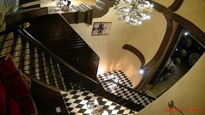 Un escalier en colimaçon avec un sol à carreaux, un lustre et un tableau encadré accroché au mur.