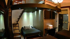 Une chambre à coucher avec un lit, un bureau et une chaise. Un escalier mène à un niveau supérieur.