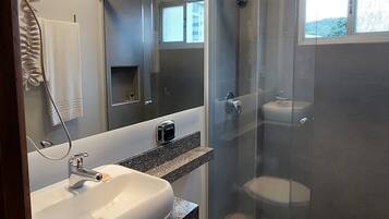 Un baño moderno con cabina de ducha de vidrio, lavamanos blanco y retrete.