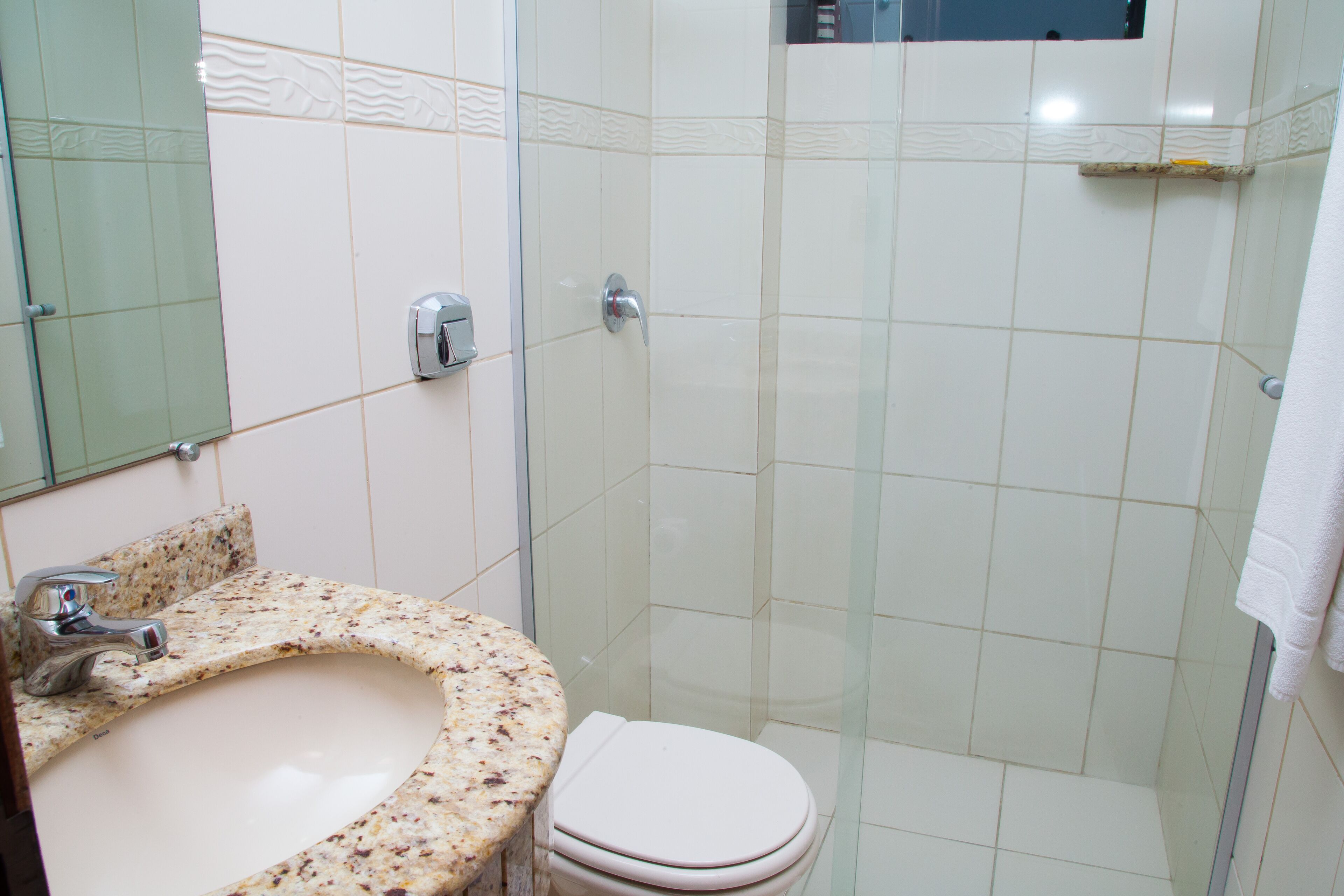 A bathroom with a marble sink, a toilet, and a glass shower enclosure.