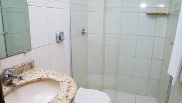 A bathroom with a marble sink, a toilet, and a glass shower enclosure.