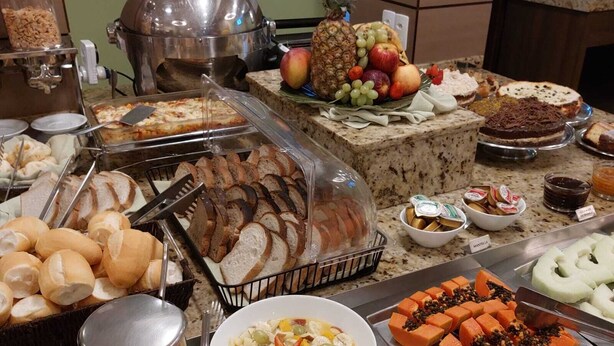 A buffet with various food items including bread, fruits, and desserts. - Hotel Príncipe (Joinville)