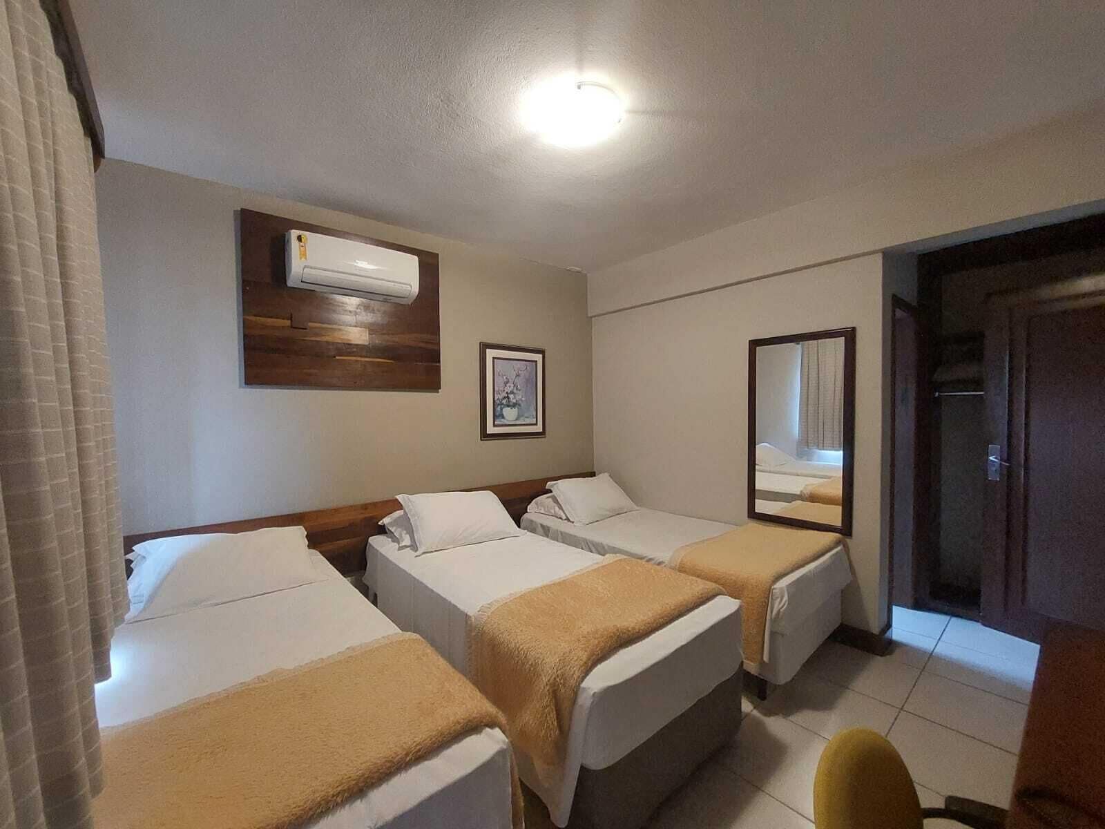A hotel room with two beds, a ceiling fan, an air conditioning unit, a framed picture, and a mirror.