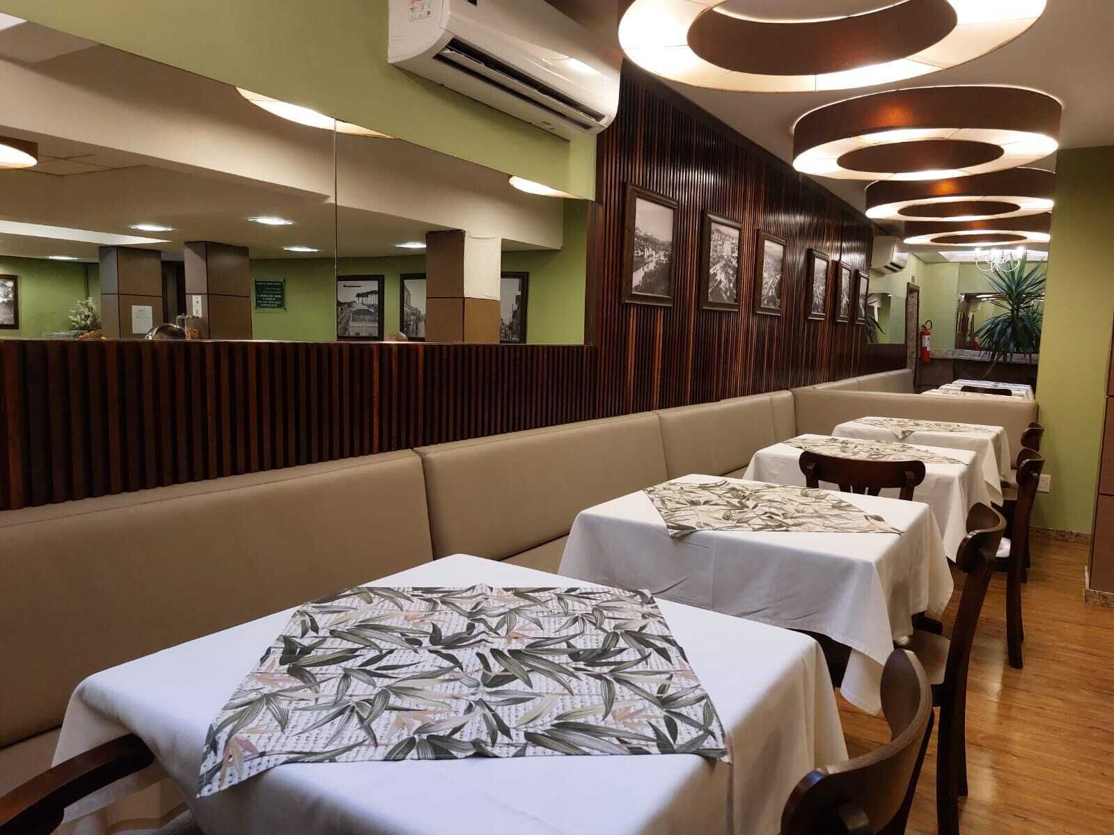 Un restaurante con cabinas y mesas, todas cubiertas con manteles blancos.