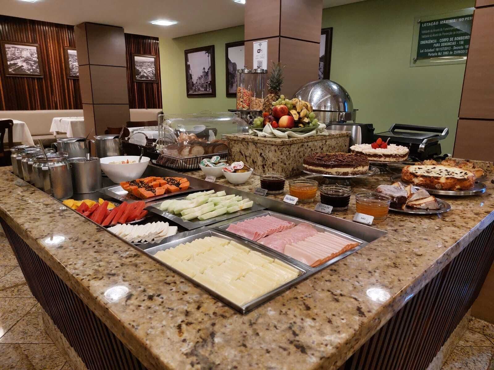 A buffet counter with various food options including fruits, meats, and desserts.