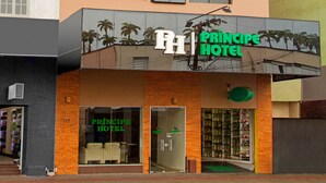 A hotel with multiple balconies, a sign reading "PRINCIPE HOTEL," and a reflection of palm trees on the glass facade. - Hotel Príncipe (Joinville)