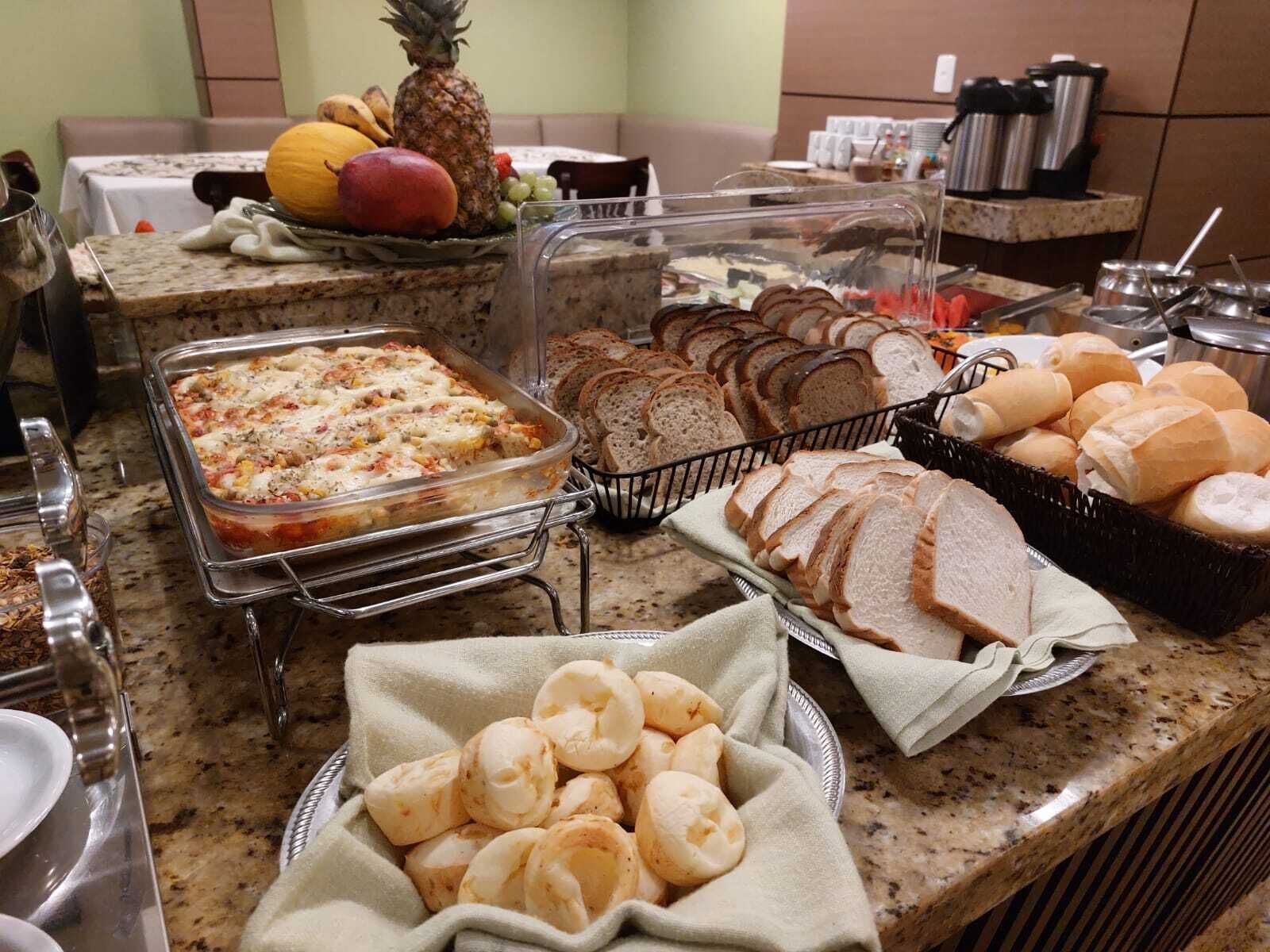 A buffet with various food items including a casserole dish, bread, and pastries.
