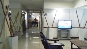 A spacious lobby with a television, seating area, and a hallway leading to another room. - Hotel Adrazi (Buenos Aires)