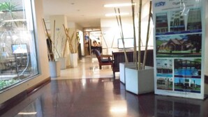 A hallway with a glossy floor, potted plants, and a seating area with a chair and table. - Hotel Adrazi (Buenos Aires)