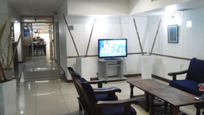A spacious living area with a television, wooden furniture, and a tiled floor. - Hotel Adrazi (Buenos Aires)