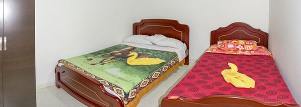 Dos camas de madera con diferentes cubrecamas, una con diseño verde y amarillo y la otra con diseño rojo y amarillo.