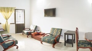 A living room with a sofa, armchairs, a coffee table, and a dining table with chairs. - Apartahotel San Miguel (San Gil)