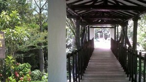 A wooden sign with text and a wooden walkway leading to a covered area. - Apartahotel San Miguel (San Gil)