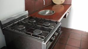 Une cuisine équipée d’une cuisinière à gaz, d’un évier et d’une planche à découper en bois.