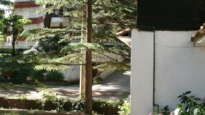 Un bâtiment traditionnel, doté d’un toit en tuiles, entouré d’une végétation luxuriante et bordé d’un sentier.