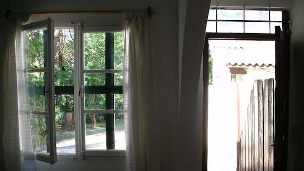 Une pièce avec une fenêtre ouverte donnant sur un jardin.
