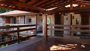 An outdoor wooden deck with a rustic ceiling, surrounded by brick walls and wooden railings. - Pousada Enseada dos Búzios (Ubatuba)