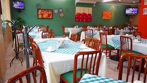 A restaurant with multiple tables and chairs, some with checkered tablecloths.