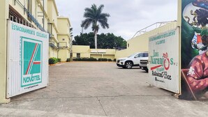 A hotel entrance with a paved driveway, a parked car, and a mural on the right. - Novotel (Poza Rica)