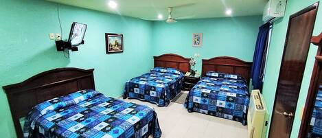A room with three beds, a ceiling fan, and two wall-mounted air conditioners.