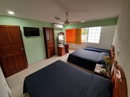Un dormitorio con dos camas, televisión, armario, escritorio y ventana con cortinas.