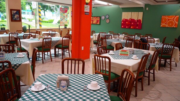 A restaurant with multiple tables and chairs, some with green checkered tablecloths. - Novotel (Poza Rica)