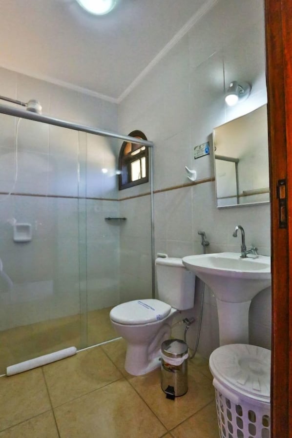 Une salle de bain avec une douche à parois de verre, des toilettes, un lavabo et un panier à linge.