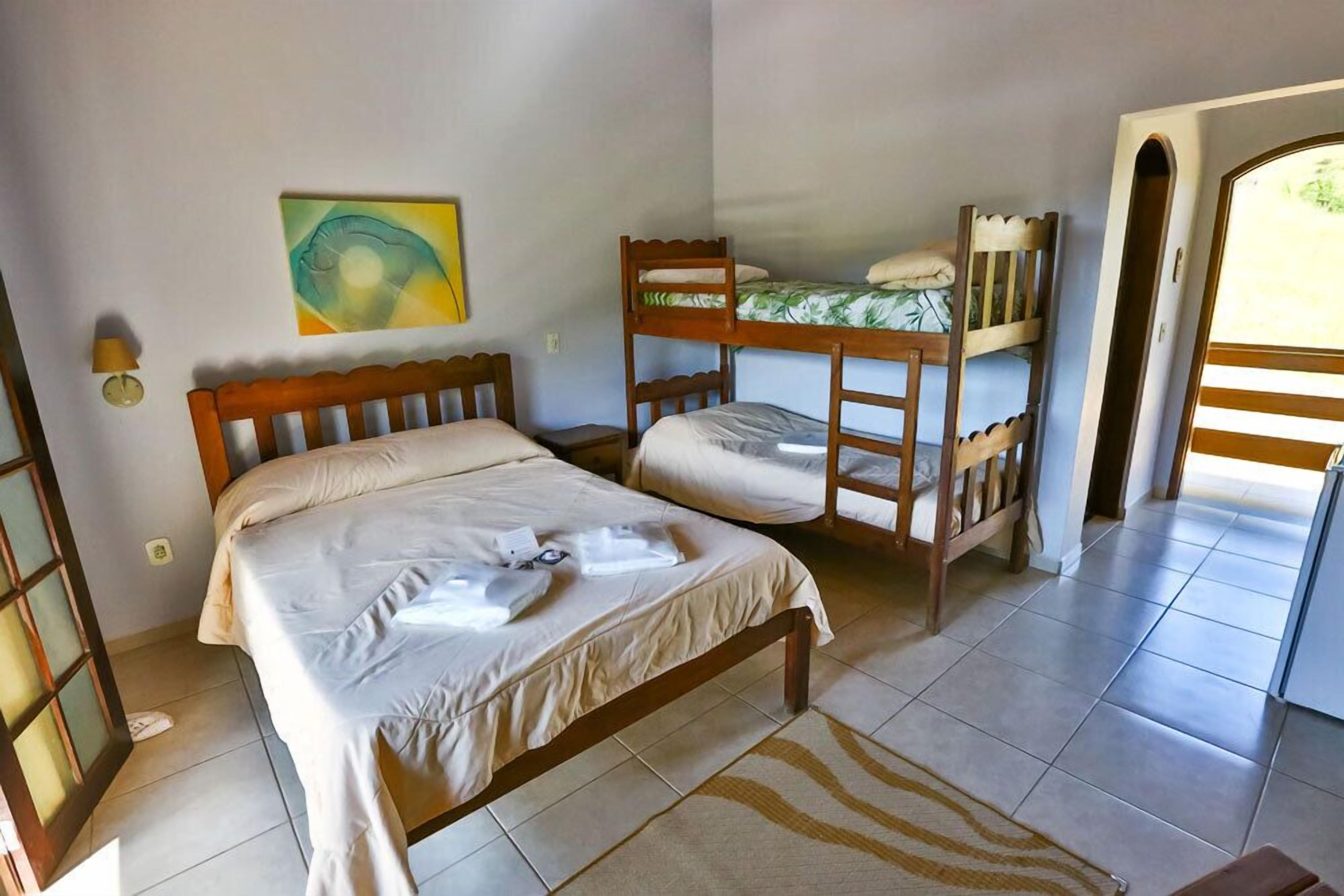 Una habitación con una cama individual, una cama litera, un tapiz a rayas de cebra, una lámpara de pared y un cuadro.