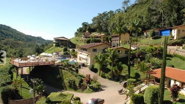 Un complexe hôtelier situé sur une colline, doté d’une piscine, de plusieurs bâtiments et d’une végétation luxuriante.