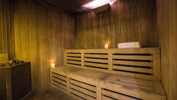 Eine Holzzu sauna mit Bänken, einer Sitzbank und einer Bank mit Handtuch, sowie eine Kerze.