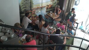 A restaurant with patrons seated at tables, a mural on the wall, and a view of the street outside. - Hotel Vial Center (Mar del Plata)