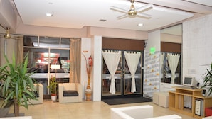 A hotel lobby with a reception desk, seating area, and a large window with curtains. - Hotel Vial Center (Mar del Plata)