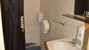 Un baño con inodoro, lavamanos y cortina de ducha.