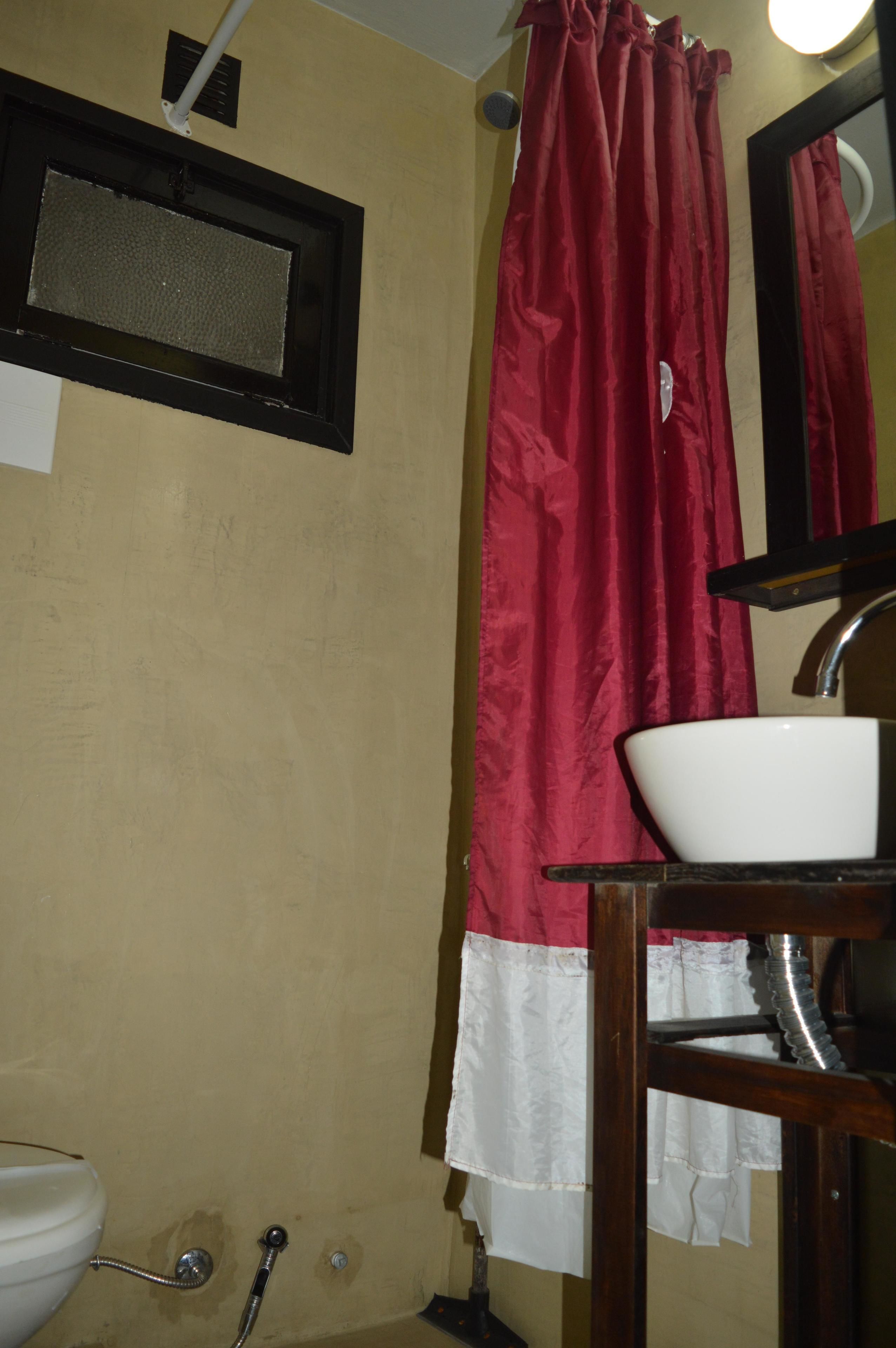 A bathroom with a white sink, a red shower curtain, and a mirror above the sink.