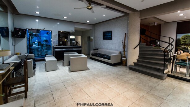 A spacious living area with a sofa, a coffee table, and a TV mounted on the wall. There is a staircase leading to another level, and a desk with a chair. - Hotel Vial Center (Mar del Plata)