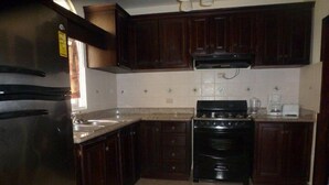 Una cocina con armarios de madera oscura, un refrigerador de acero inoxidable, una estufa y una cafetera.