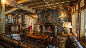 A rustic interior with a stone fireplace, leather sofas, and wooden beams. - Huilo Huilo Marina del Fuy (Panguipulli)