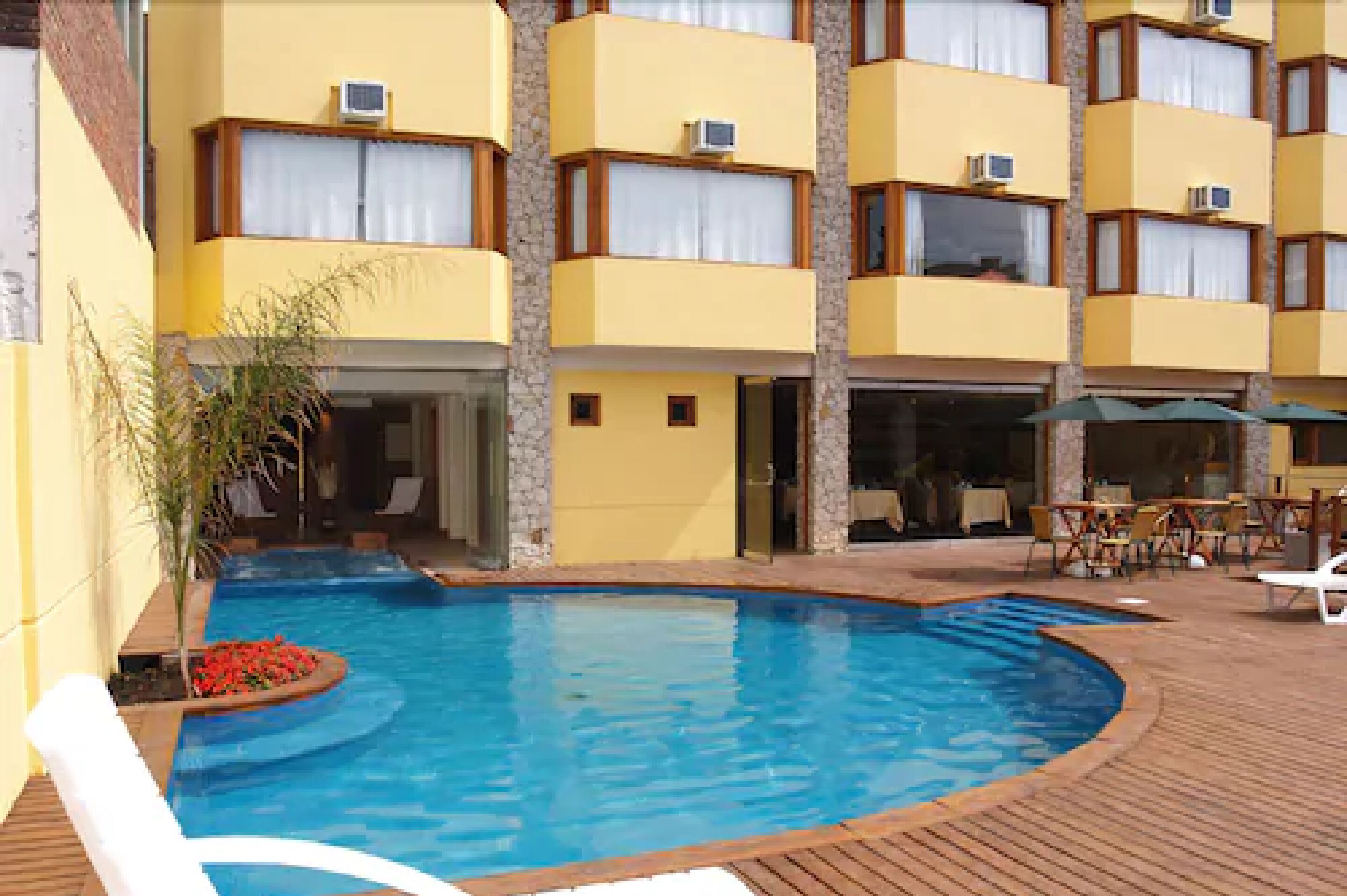 Een hotel met een zwembad, terras en een gebouw met balkons.