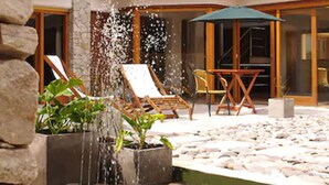 Un patio de hotel con piso de piedra, asientos al aire libre y una fuente de agua.