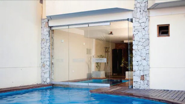 Zona de piscina con entrada de puerta de cristal, pared de piedra y una ventana pequeña.