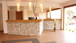 Un área de recepción con mostrador de piedra, escritorio de madera y lámparas colgantes.