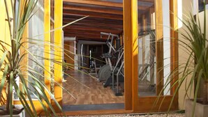 Un gimnasio con equipamiento de ejercicio, suelo de madera y ventanas amplias.