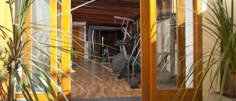 A gym with exercise equipment, wooden flooring, and large windows.