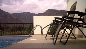 A poolside area with a view of mountains, a pool, and outdoor chairs. - Posada Vista Tepoz (Tepoztlán)