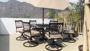 A terrace with a table and chairs, an umbrella, and a view of mountains. - Posada Vista Tepoz (Tepoztlán)