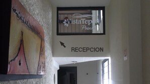A hallway with a reception area, a wall-mounted sign for Vista Tepes Posada, and a large painting on the left. - Posada Vista Tepoz (Tepoztlán)