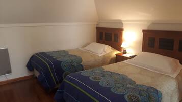 Two single beds with floral-patterned bedding, a bedside table with a lamp, and a wooden headboard.