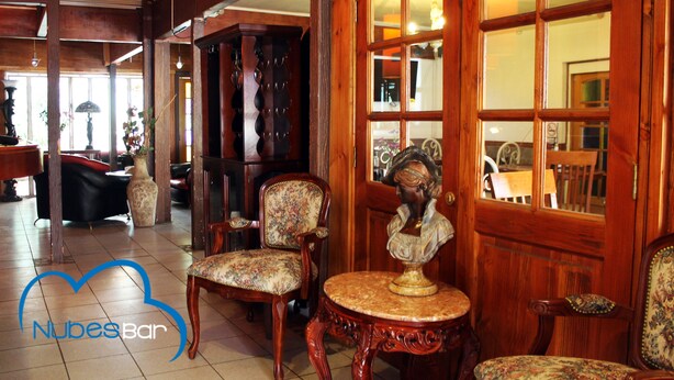 Una habitación con muebles de madera, un busto sobre una mesa y un ventanal con vistas.
