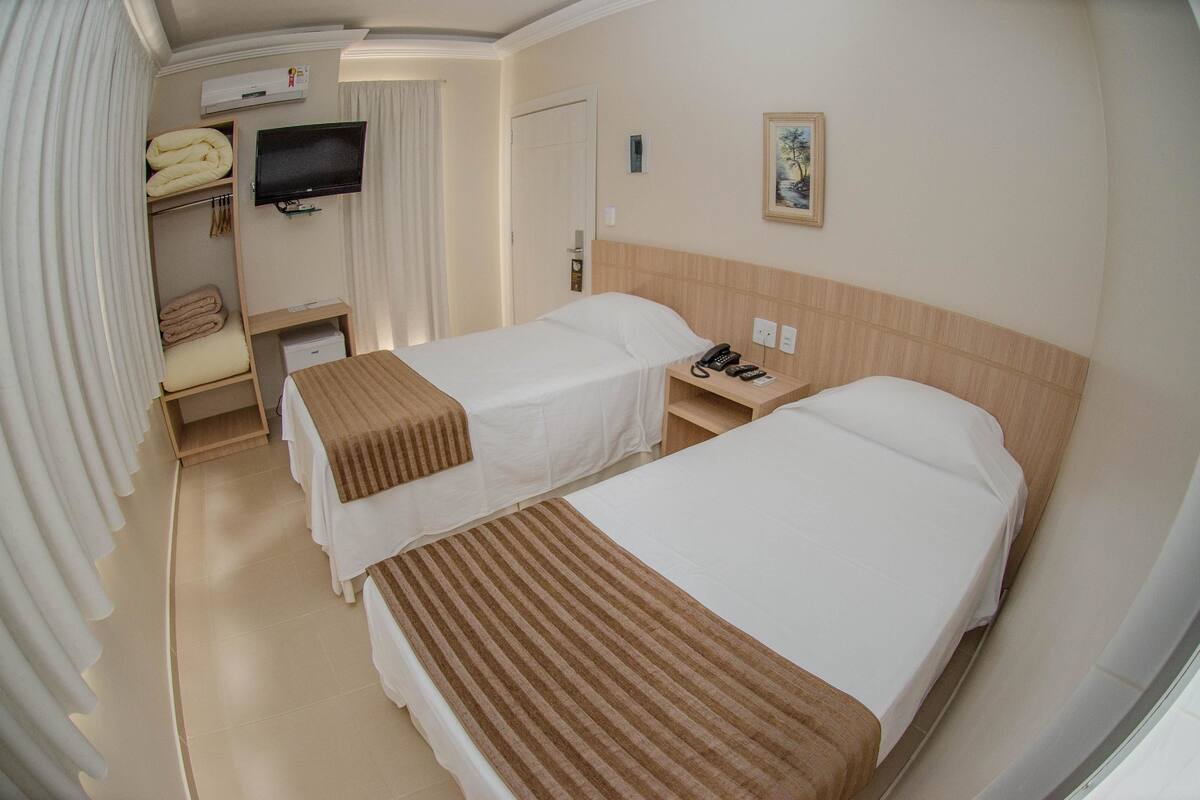 Ein Hotelzimmer mit zwei Betten, einem Fernseher, einem Gemälde und einem Telefon.